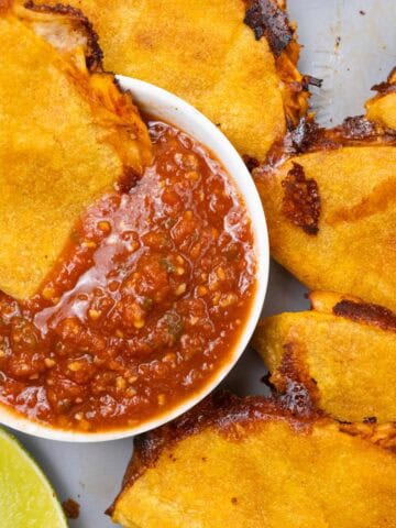 Crispy Shredded Chicken Tacos Finished with Salsa and lime Closeup